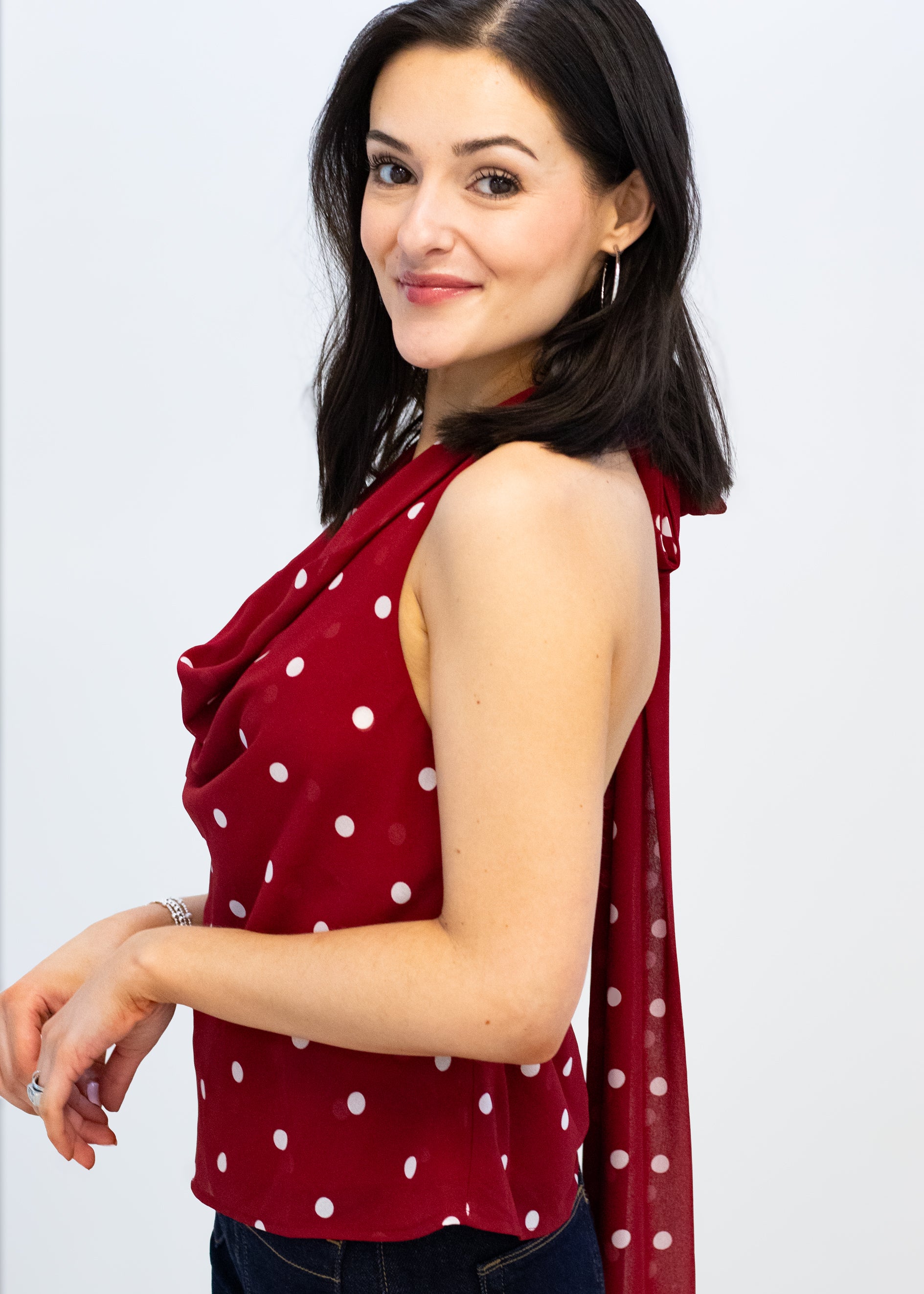 Woman wearing a red polka dot top with a matching scarf on a white background