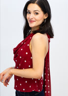 Woman wearing a red polka dot top with a matching scarf on a white background