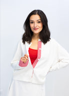 Woman wearing a white coat over a red shirt on a light gray background