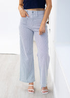 Person wearing light blue striped pants and a navy top on a white background