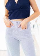 Person wearing a navy top and light blue striped pants on a white background