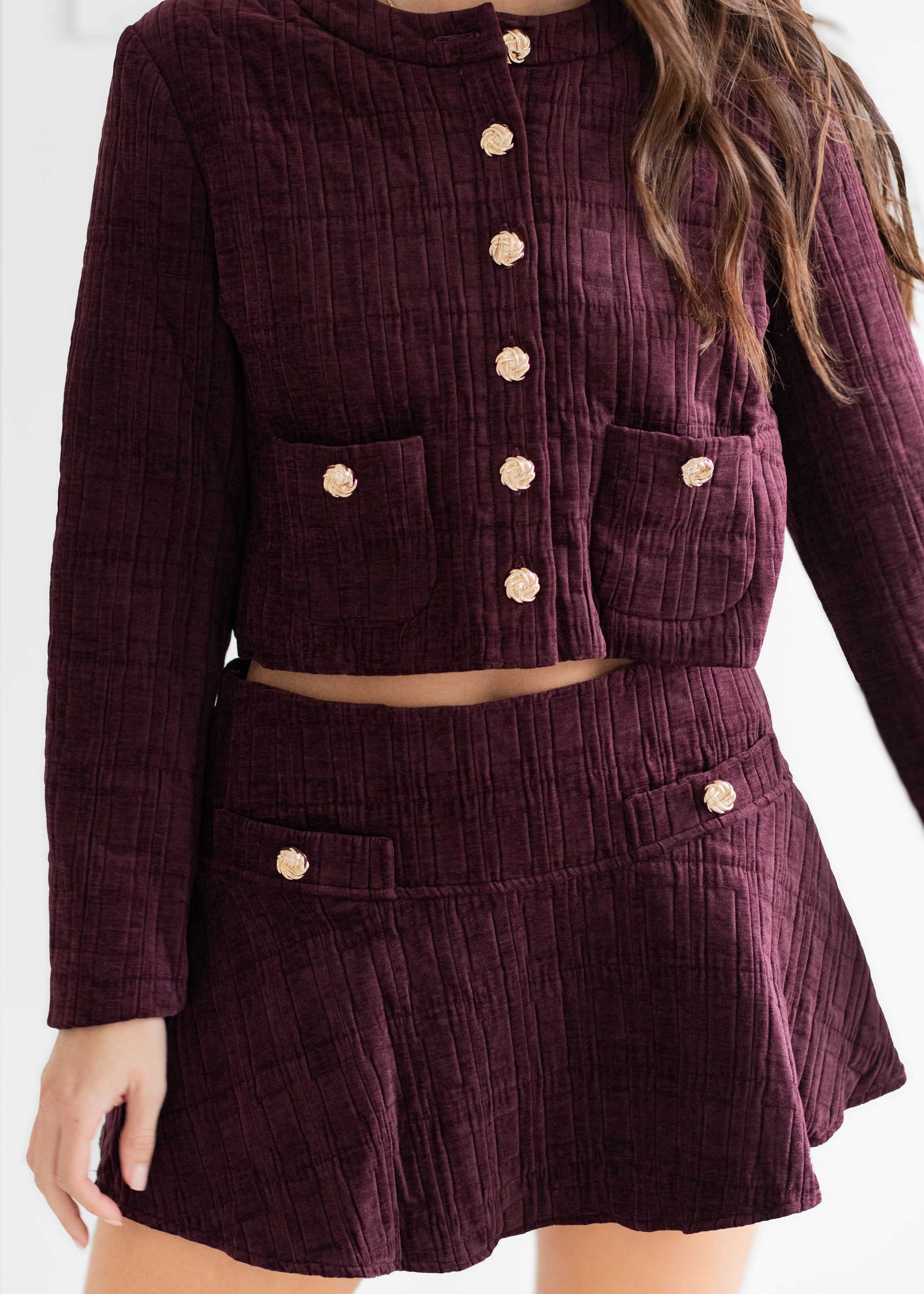 Purple corduroy outfit with button details on a plain background