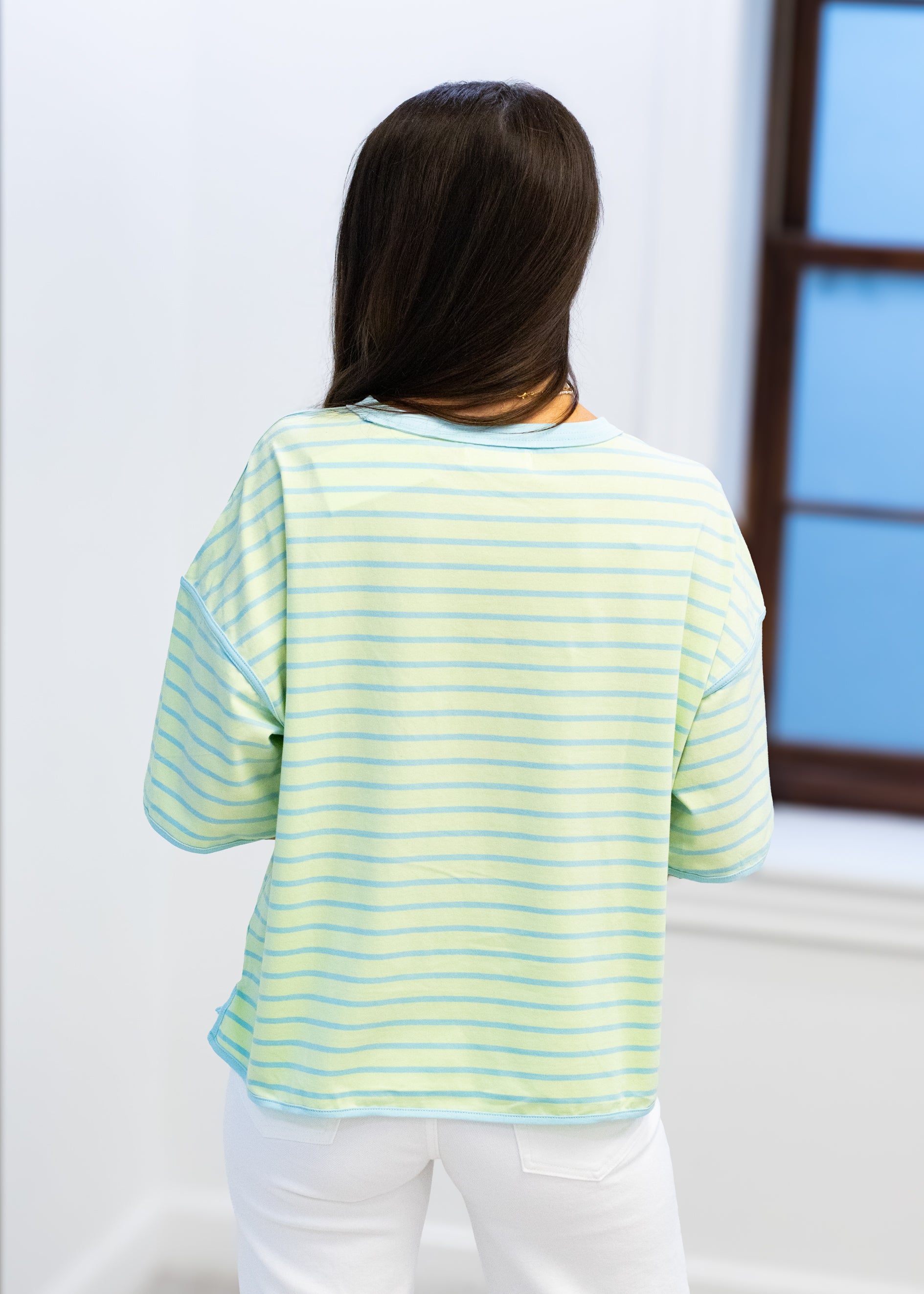 Person wearing a light green and yellow striped shirt in a minimal indoor setting
