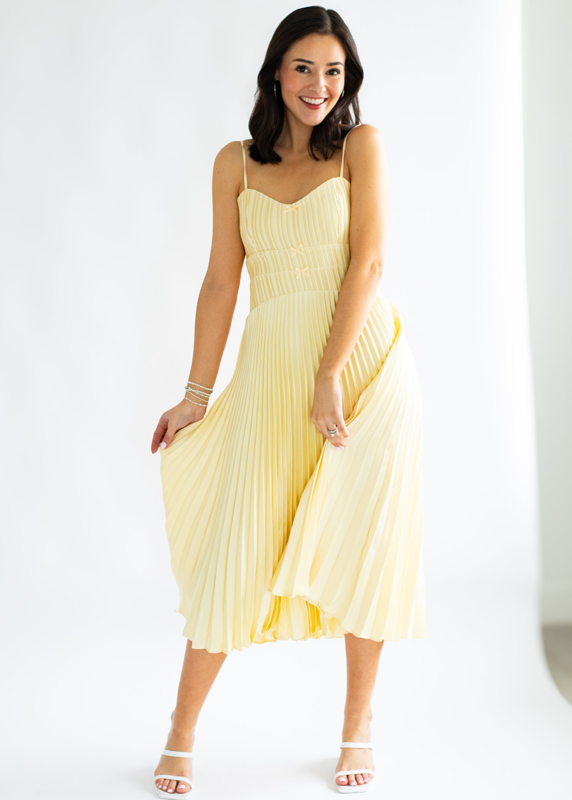 Woman wearing a yellow pleated dress on a white background