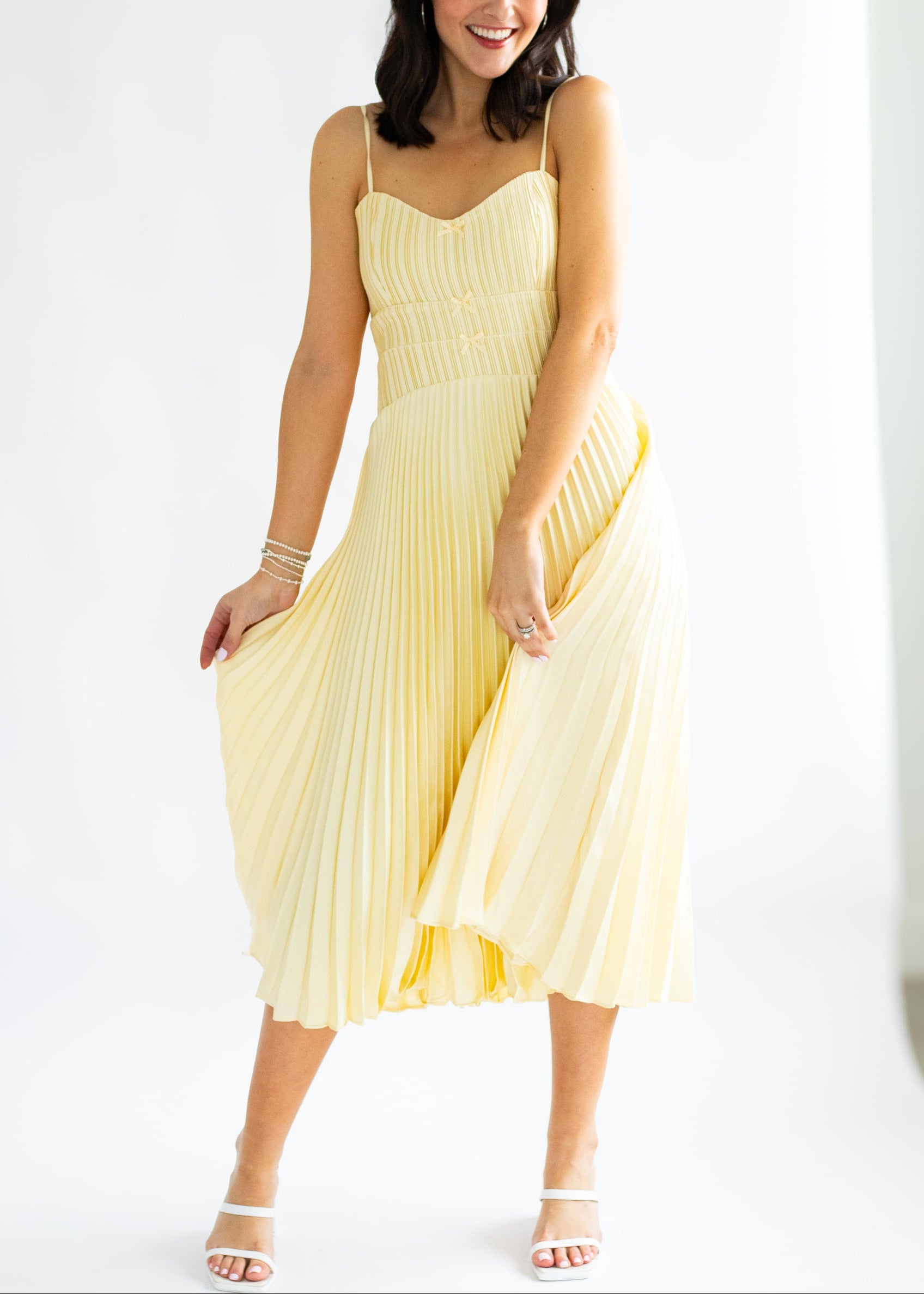 Woman wearing a yellow pleated dress on a white background