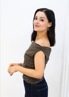 Woman wearing an off-shoulder green top against a white background