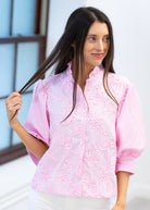 Woman wearing a pink patterned blouse with a blurred background