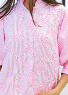 Close-up of a pink and white striped shirt with floral embroidery