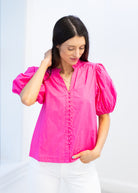 Woman wearing a bright pink blouse with puff sleeves against a light background