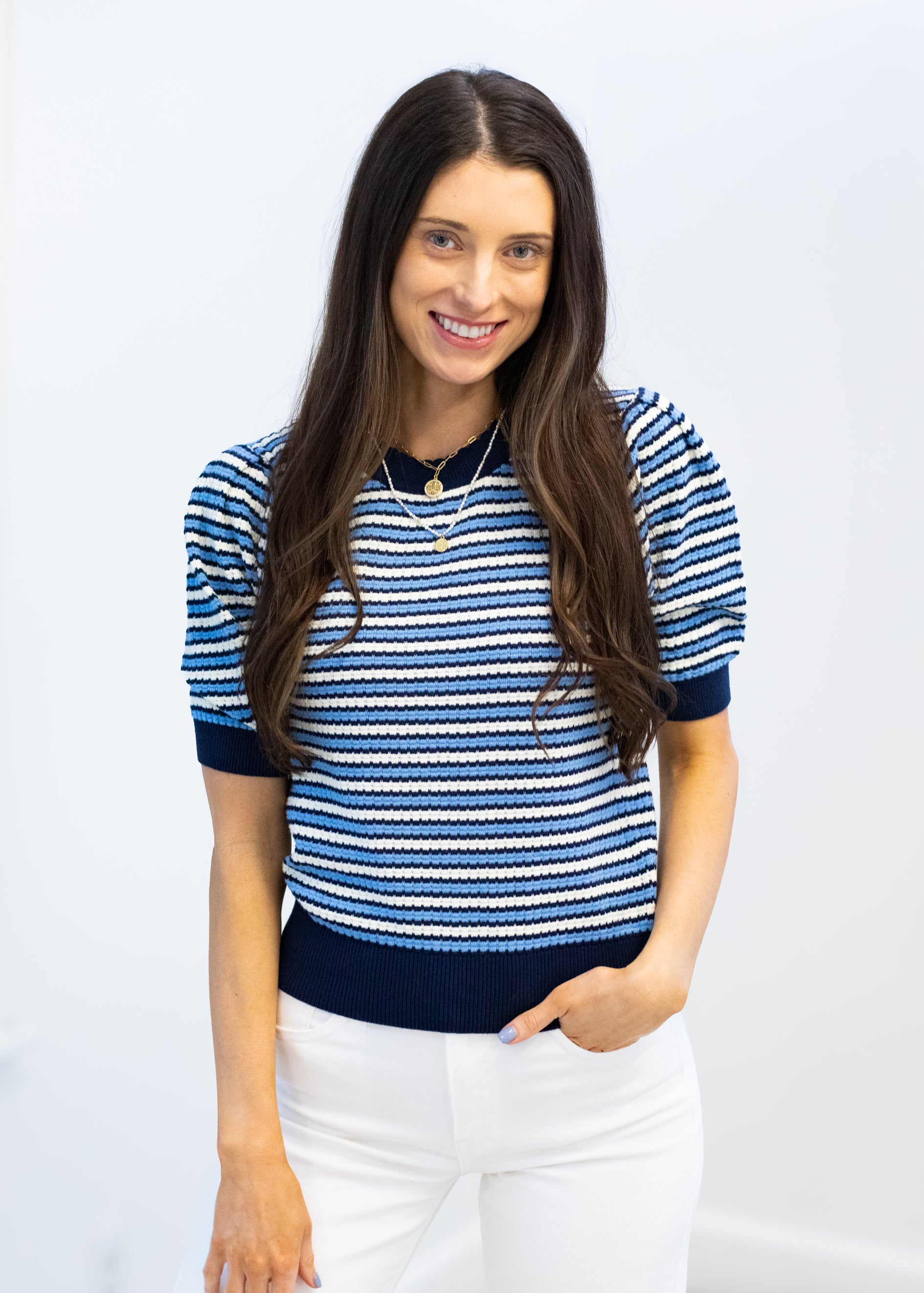 Woman wearing a blue and white striped shirt with a plain background