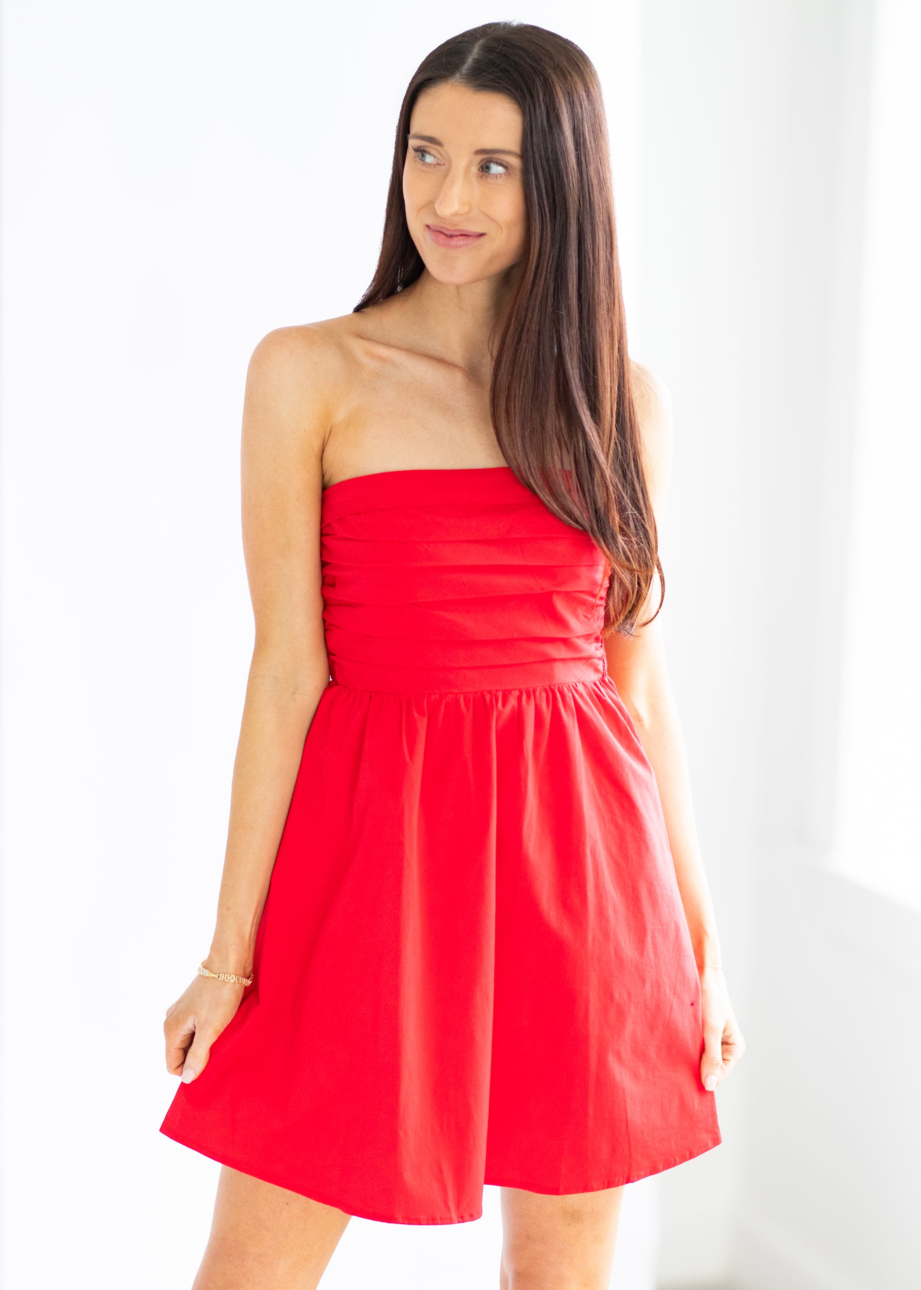 Woman wearing a strapless red dress against a white background