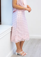 Person wearing a pink lace skirt with black polka dots on a white background