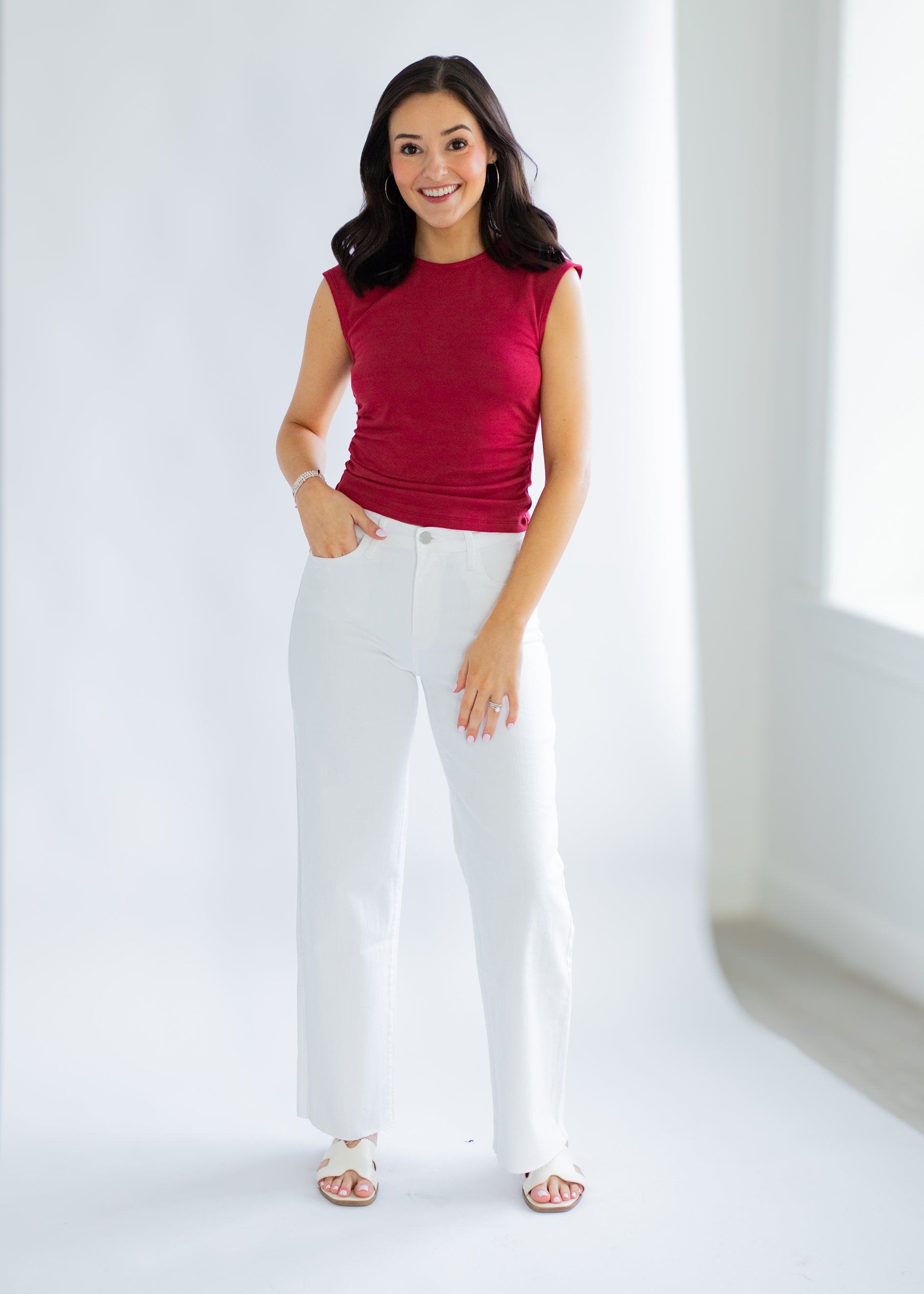 Woman wearing a red top and white pants on a white background