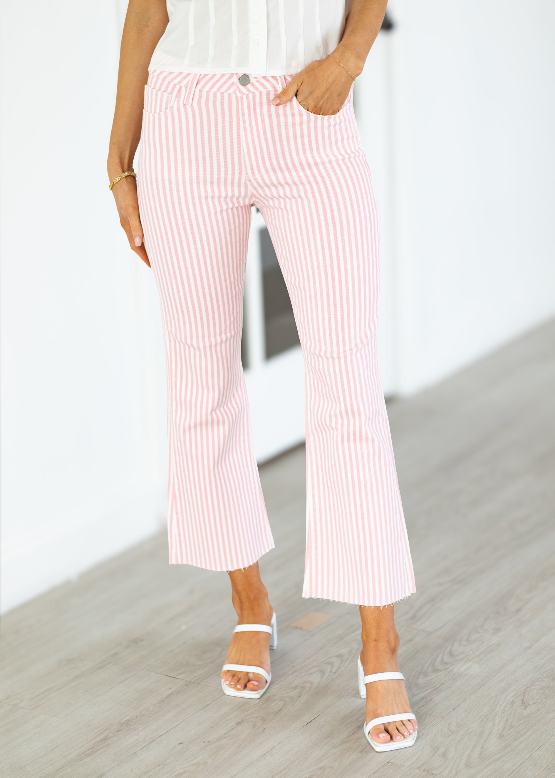 Person wearing pink and white striped pants on a light wooden floor.