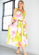 Woman wearing a floral dress with pink and green colors on a beige background