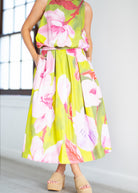 Woman wearing a floral dress with pink and green colors on a beige background