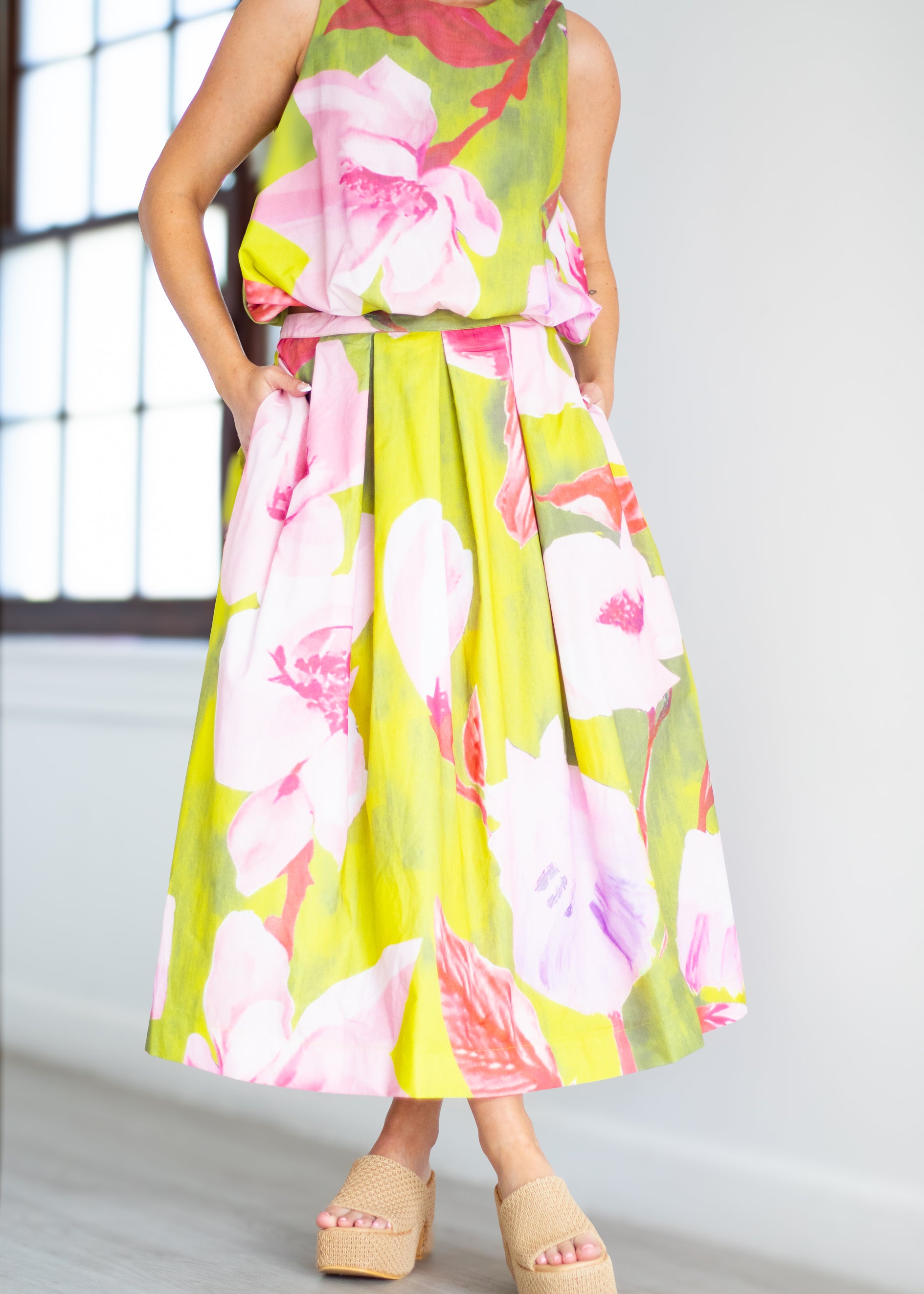Woman wearing a floral dress with pink and green colors on a beige background