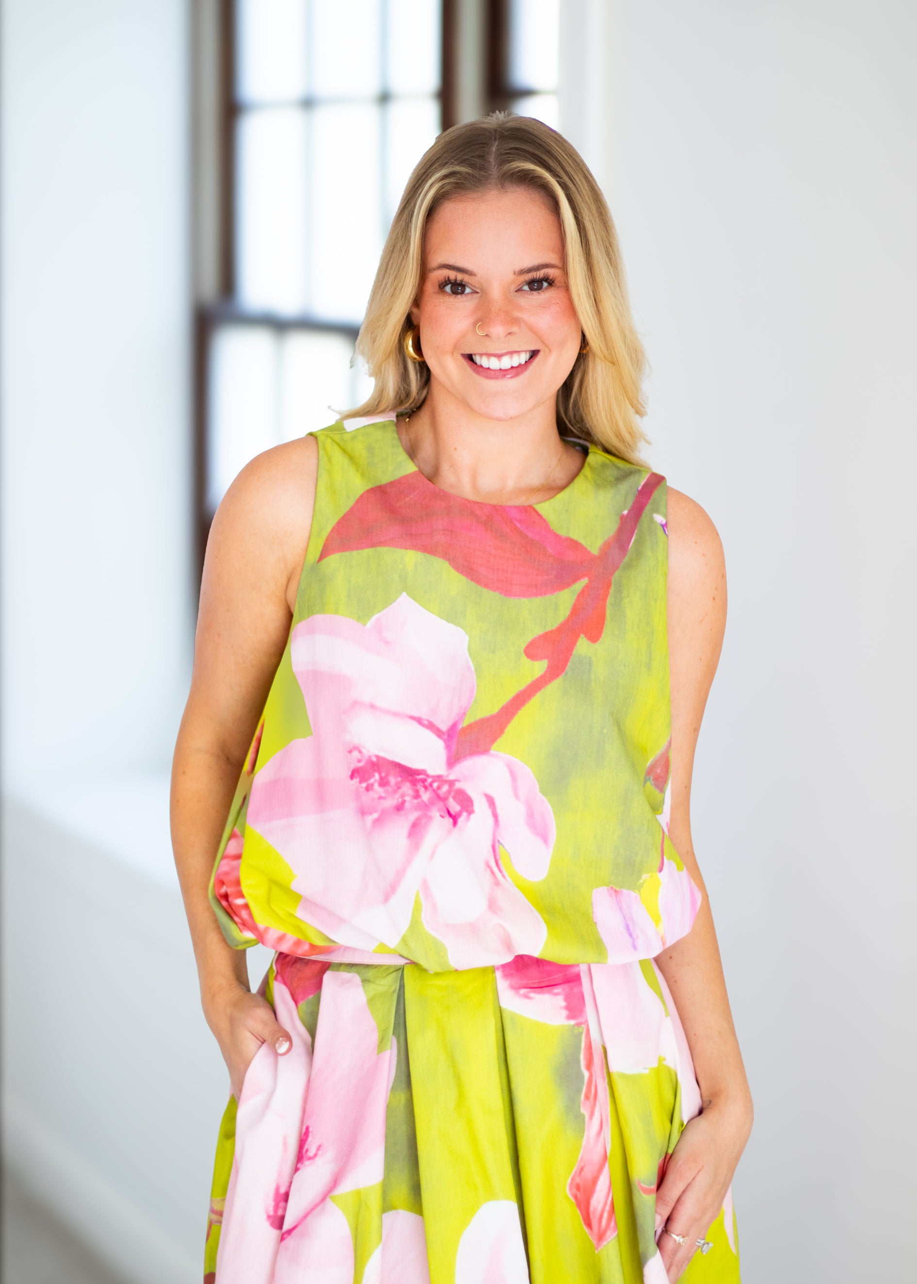 Woman wearing a floral dress with pink and green colors on a beige background