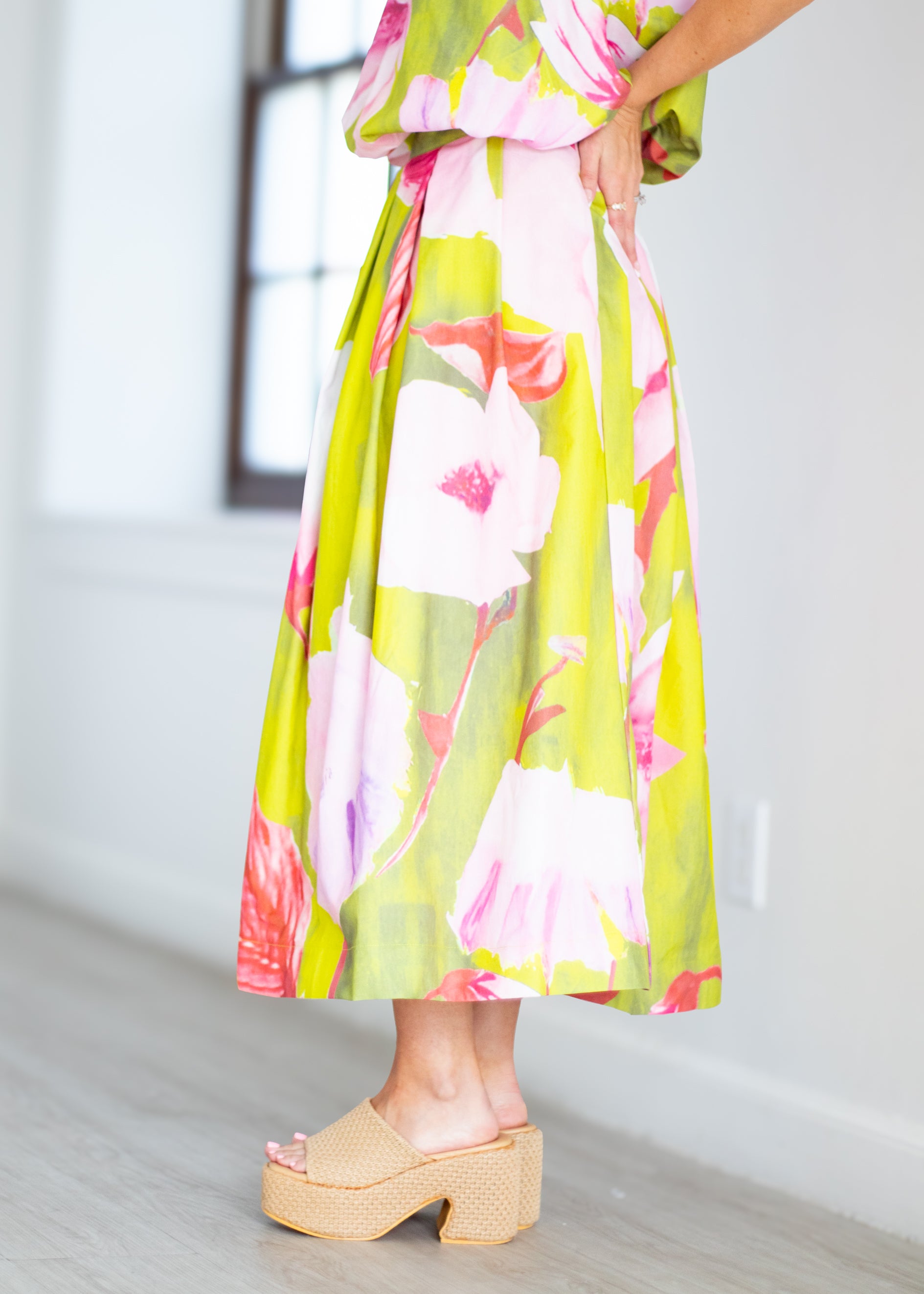 Woman wearing a floral dress with pink and green colors on a beige background