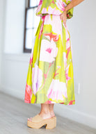 Woman wearing a floral dress with pink and green colors on a beige background