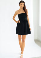 Woman wearing a black strapless dress on a white background