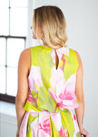 Woman wearing a floral dress with pink and green colors on a beige background