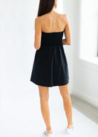 Woman wearing a black strapless dress in a minimal indoor setting