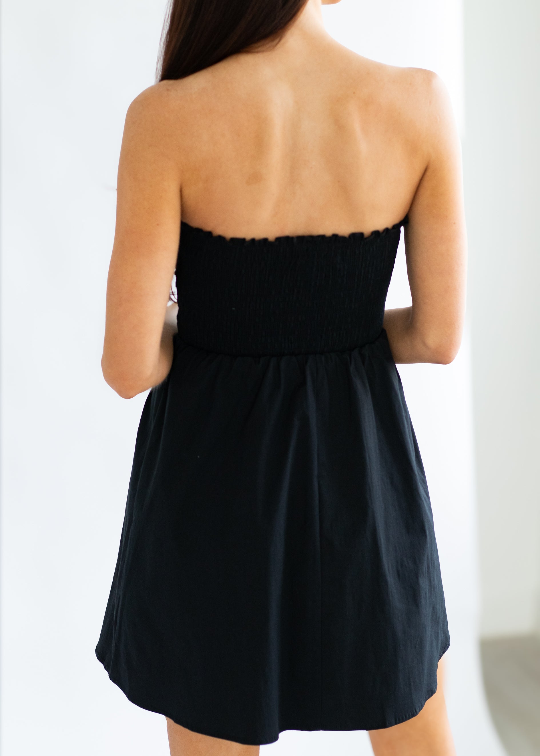 Black strapless dress worn by a person on a white background