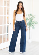 Woman wearing blue jeans and a white top in a bright room.