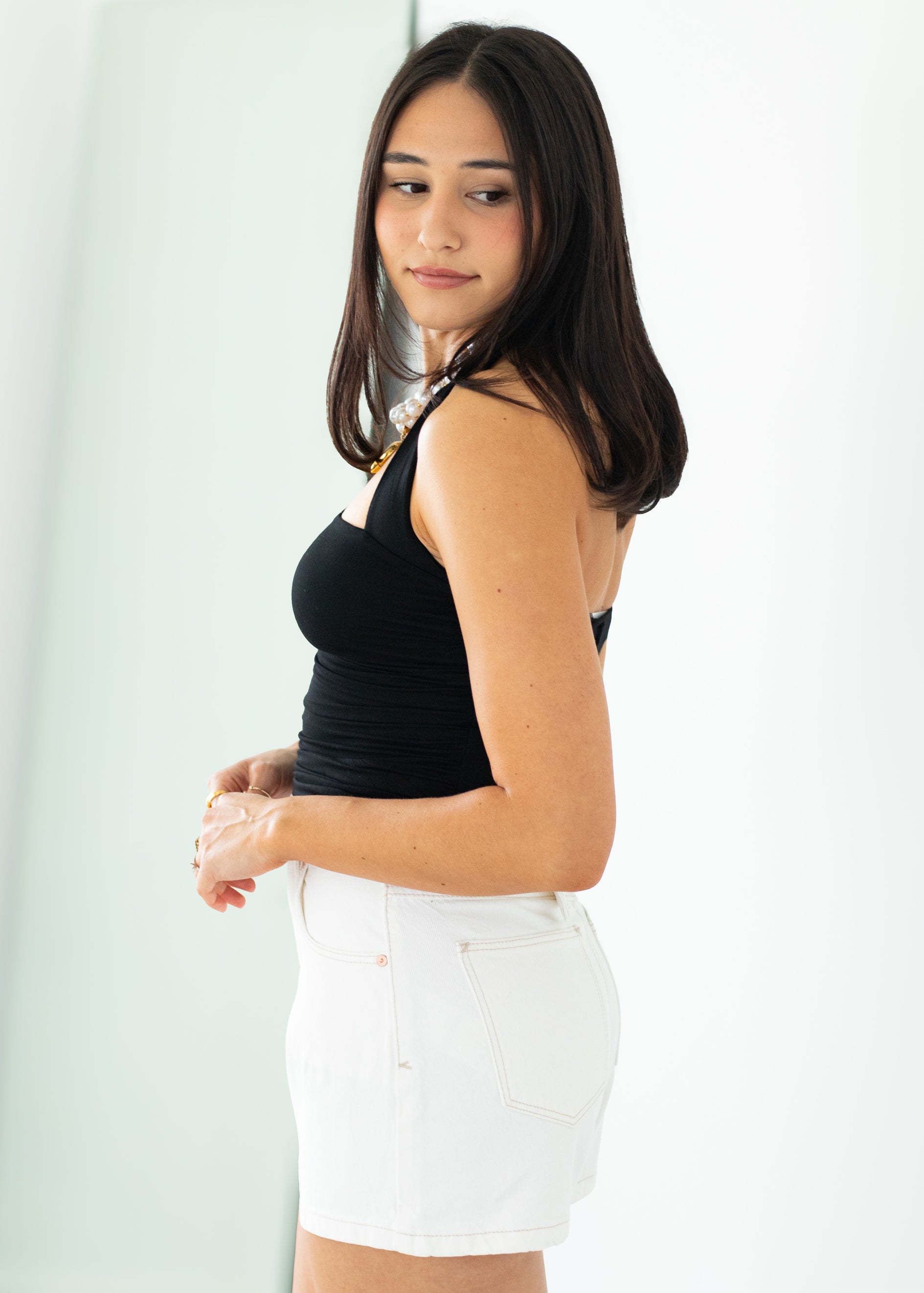 Woman wearing a black tank top and white shorts on a plain background
