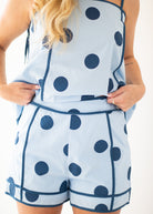 Woman wearing a blue polka dot dress against a beige background