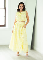 Woman wearing a yellow lace outfit standing in a bright room.