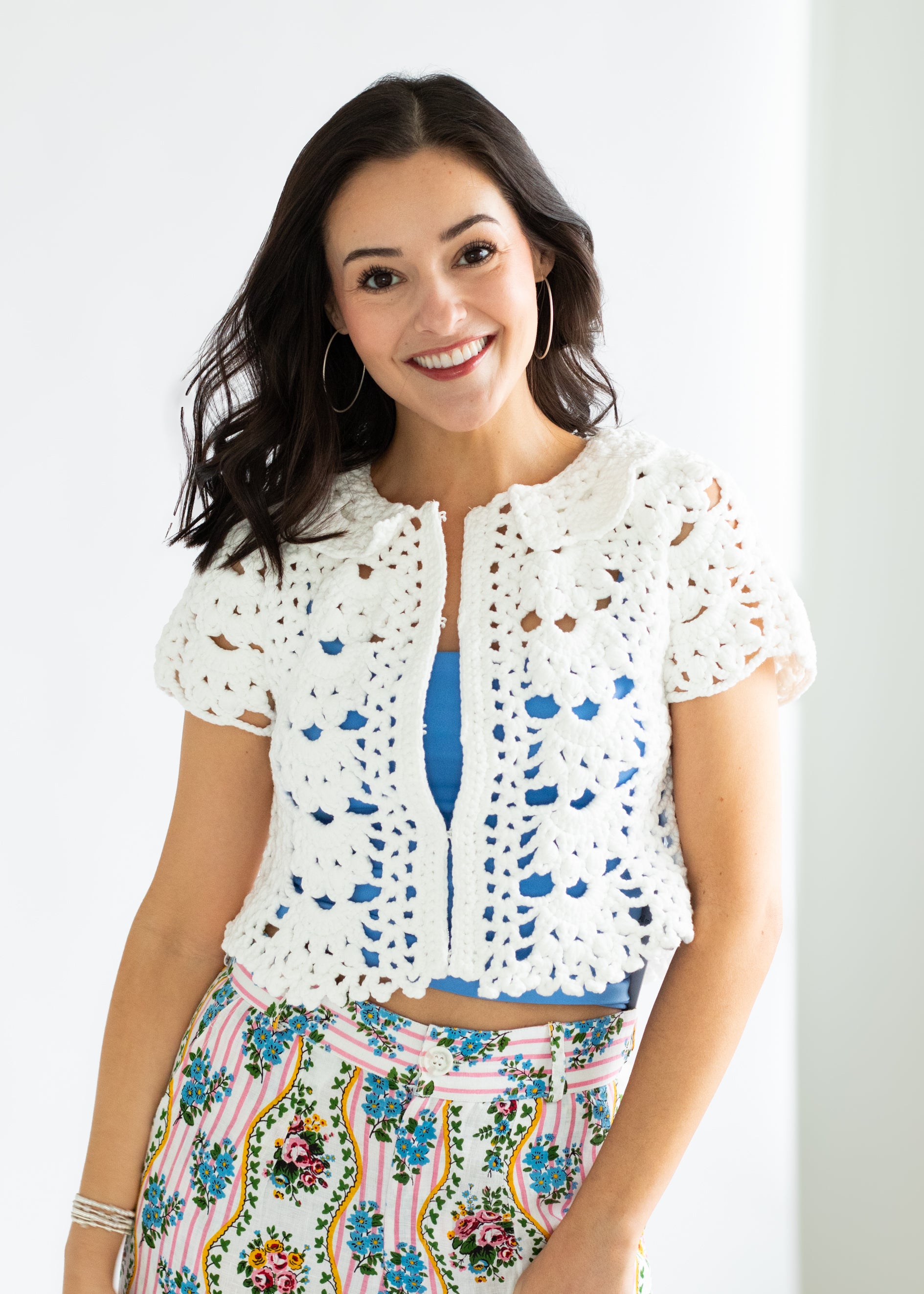 Woman wearing a white crochet top with a colorful skirt against a white background