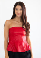 Woman wearing a red strapless top against a white background