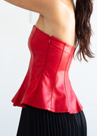 Red leather top worn by a person on a white background
