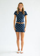 Woman wearing a navy blue outfit with white star patterns on a plain background