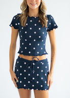 Woman wearing a navy blue outfit with white star patterns on a plain background
