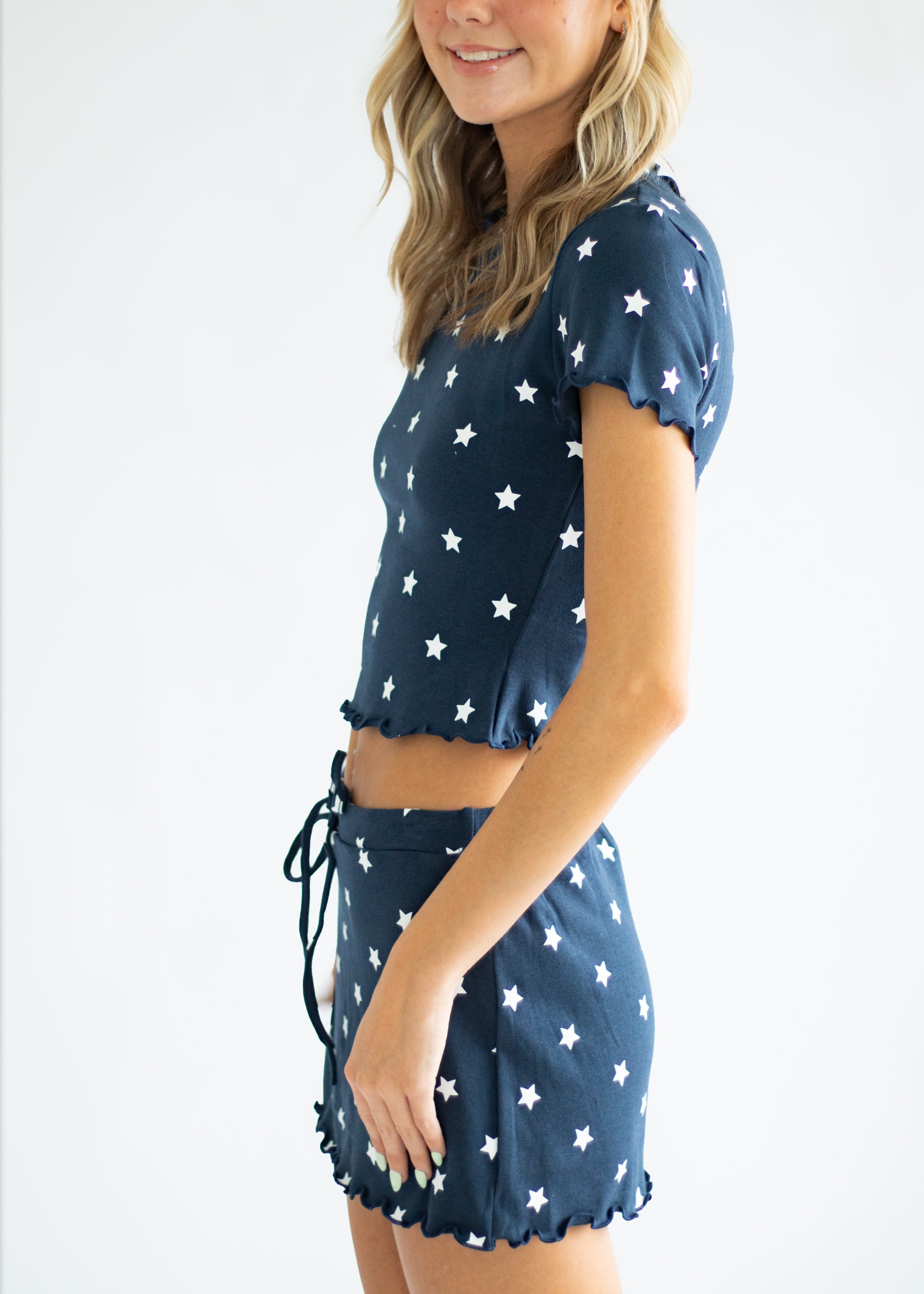 Woman wearing a navy blue outfit with white star patterns on a plain background