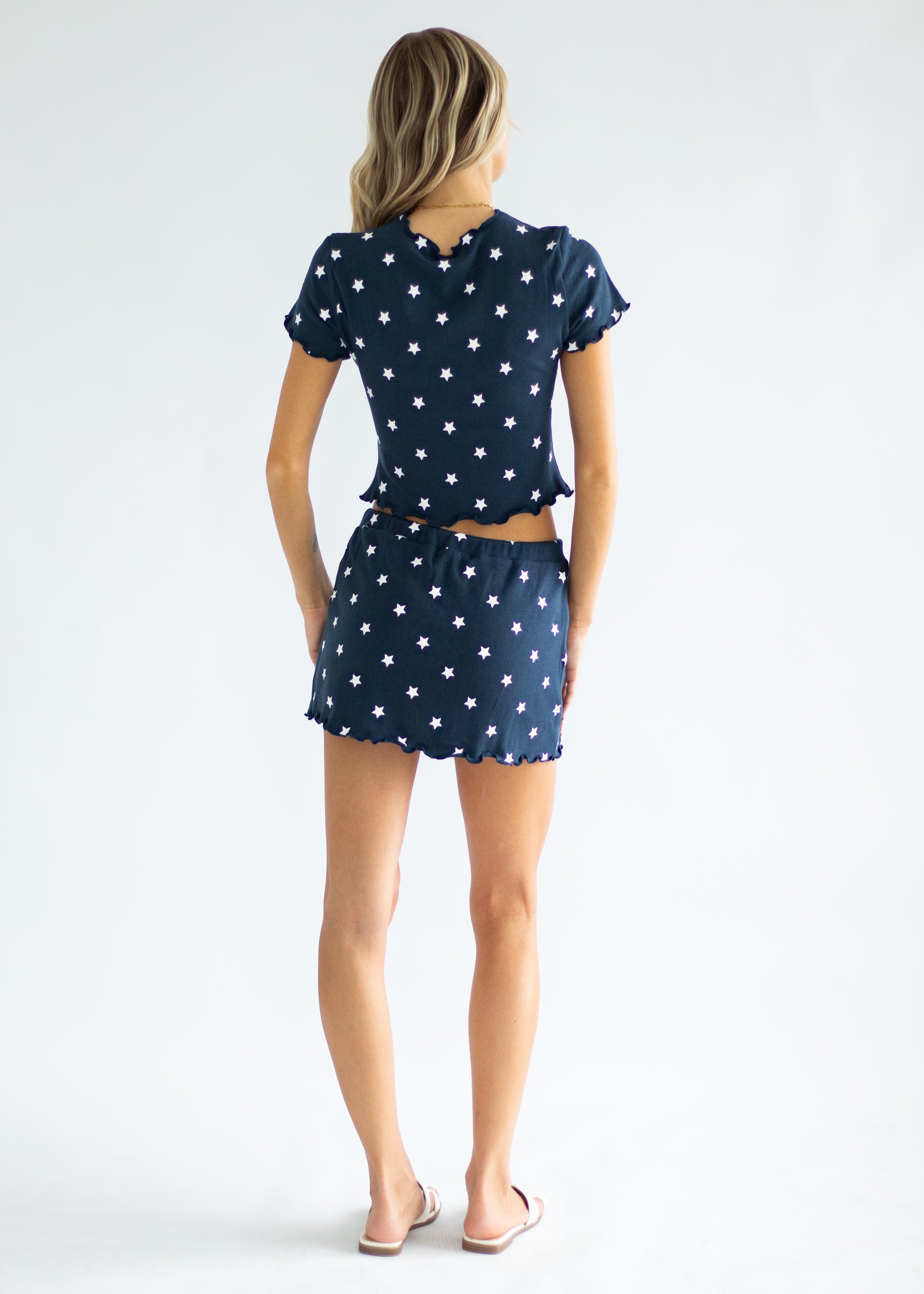 Woman wearing a navy outfit with white star pattern on a plain background