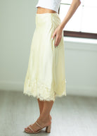 Light yellow lace skirt worn by a person on a plain background