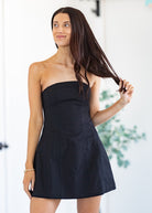 Woman wearing a black strapless dress with a blurred background