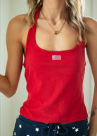 Red tank top with an American flag patch worn by a person against a neutral background