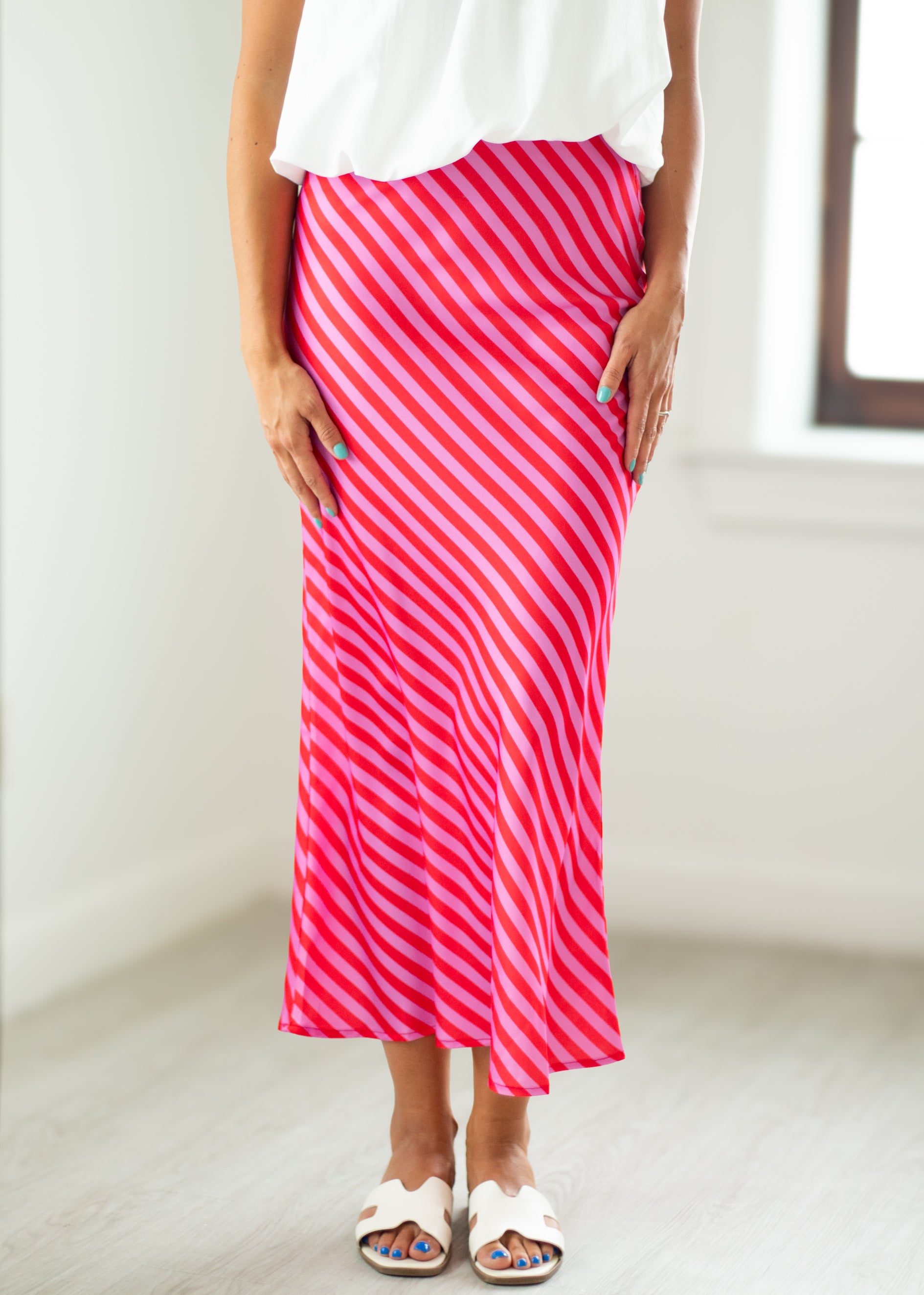 Person wearing a pink and white striped skirt with a white top indoors.