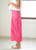 Person wearing a white top and pink striped skirt in a minimal indoor setting