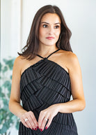 Woman wearing a black pleated dress against a light background