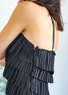 Black ruffled dress worn by a person with a blurred background