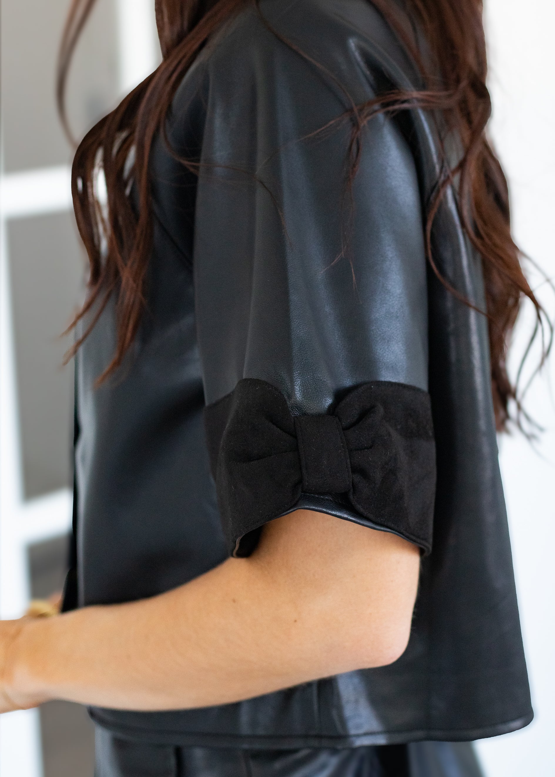 Person wearing a black leather outfit with a bow detail on a white background