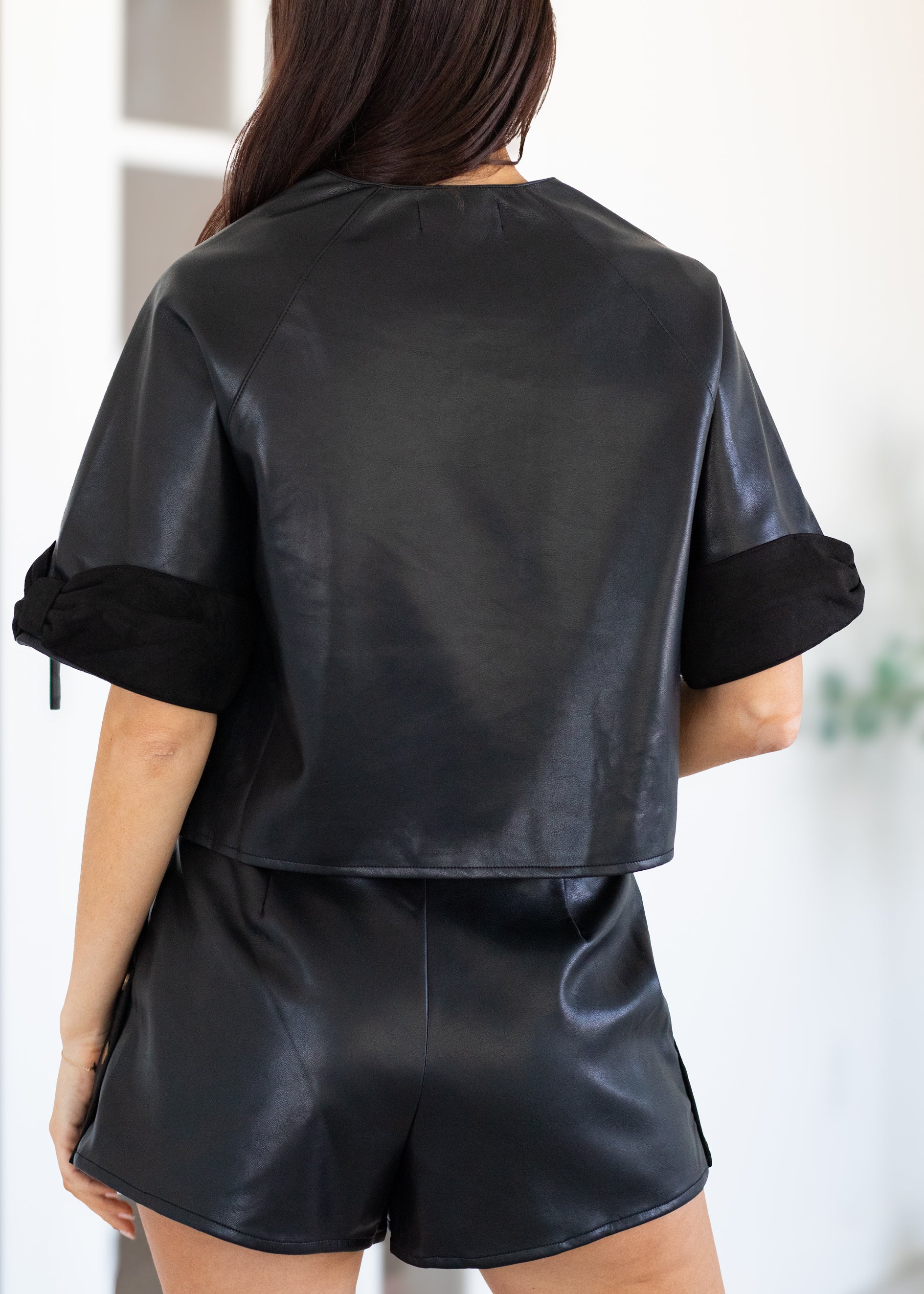 Person wearing a black satin outfit with a plain background