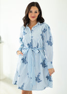 Woman wearing a blue and white striped dress with floral patterns on a white background