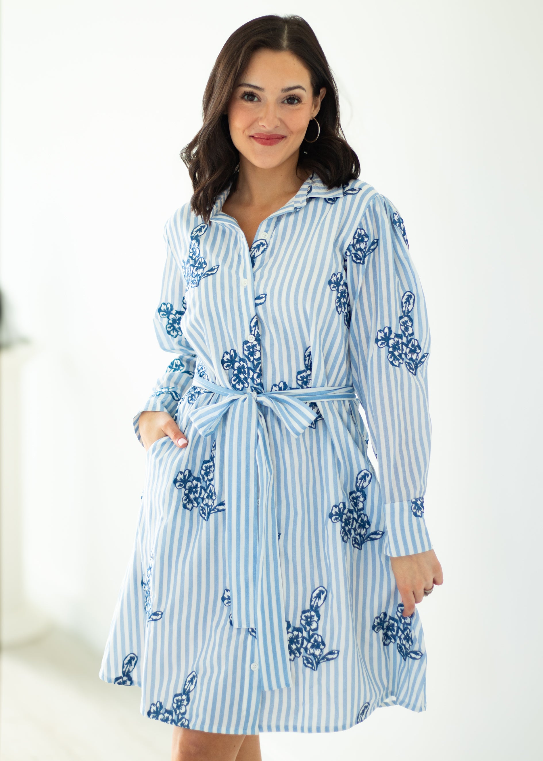 Woman wearing a blue and white striped dress with floral patterns on a white background
